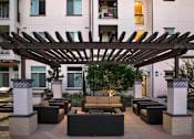 Thumbnail 95 of 114 - A patio with a wooden pergola and black couches.