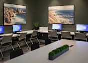 Thumbnail 94 of 114 - A room with a long table and chairs, two large landscape pictures on the wall, and a row of computer monitors.