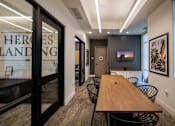 Thumbnail 79 of 114 - A conference room with a long table and chairs, a television, and a glass wall with the word "HEROES" on it.