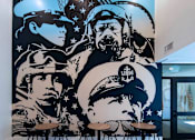 Thumbnail 80 of 114 - A mural of military personnel is displayed on a wall.