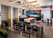Thumbnail 78 of 114 - A room with a long table and chairs in front of a wall with a vintage car poster.