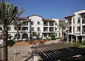 Thumbnail 72 of 114 - A sunny day at the apartment complex with palm trees and a basketball court.