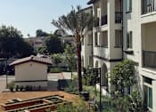 Thumbnail 65 of 114 - A courtyard with a white building and a small building in the background.