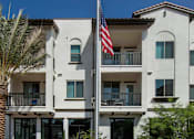 Thumbnail 69 of 114 - A white building with a balcony and a flag on a pole.