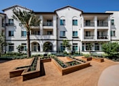 Thumbnail 60 of 114 - A large white building with a balcony on the second floor and a palm tree in front.