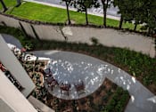 Thumbnail 59 of 114 - A circular patio with chairs and a table is surrounded by a garden.