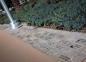 Thumbnail 41 of 114 - A memorial with names and a hammer is in front of a bush.