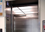 Thumbnail 54 of 114 - A stainless steel elevator with a black control panel and a star symbol on the wall.
