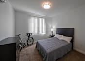 Thumbnail 7 of 114 - A bedroom with a bed, nightstand, and a bicycle.