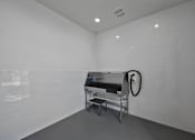 Thumbnail 14 of 114 - A white tiled room with a table and a hose.