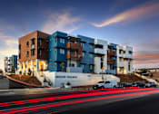 Thumbnail 9 of 103 - A modern apartment complex named Milejo Village is shown with cars passing by on the street.