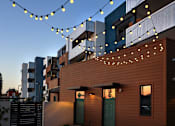 Thumbnail 28 of 103 - A building with a brown facade and string lights hanging in front.
