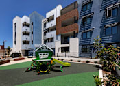 Thumbnail 3 of 103 - A playground with a green slide and a white building in the background.