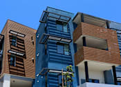 Thumbnail 58 of 103 - A modern multi-story building with blue and brown exterior.