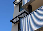 Thumbnail 72 of 103 - A tall building with balconies and a blue sky in the background.