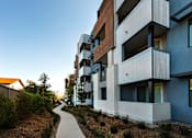 Thumbnail 64 of 103 - A modern apartment building with a walkway in front.