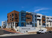 Thumbnail 63 of 103 - A modern building complex named Milejo Village under a clear blue sky.