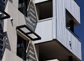 Thumbnail 70 of 103 - A white building with black balconies and windows.