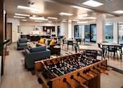 Thumbnail 30 of 103 - A foosball table is in the middle of a room with couches and chairs.