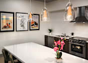 Thumbnail 37 of 103 - A kitchen with a white table and black appliances.