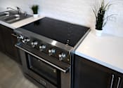 Thumbnail 42 of 103 - A modern kitchen with a stainless steel oven and a white countertop.