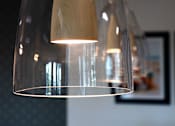 Thumbnail 53 of 103 - A modern hanging lamp with a wooden shade is suspended from the ceiling.