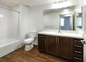 Thumbnail 86 of 103 - A white toilet sits in a bathroom with wood floors and brown cabinets.