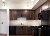 Thumbnail 92 of 103 - A kitchen with dark wood cabinets and a black refrigerator.