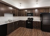 Thumbnail 95 of 103 - A kitchen with dark wood cabinets and appliances.