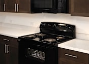Thumbnail 97 of 103 - A black stove in a kitchen with wooden cabinets.