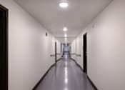 Thumbnail 94 of 103 - A long, narrow hallway with doors on both sides and recessed lighting on the ceiling.