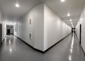 Thumbnail 91 of 103 - A long hallway with white walls and a red fire extinguisher on the wall.