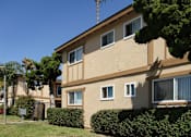 Thumbnail 5 of 9 - A beige building with a brown roof and a tree in front.
