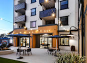 Thumbnail 82 of 94 - A modern apartment building with a patio and outdoor furniture.