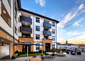 Thumbnail 92 of 94 - A modern apartment building with a patio area and outdoor furniture.