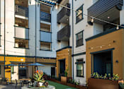 Thumbnail 86 of 94 - A modern building with a courtyard and blue chairs.