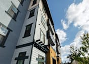 Thumbnail 90 of 94 - A modern building with a white and black exterior and a stone wall.