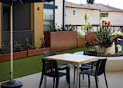 Thumbnail 68 of 94 - A patio with a table and chairs under an umbrella.