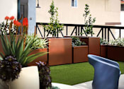 Thumbnail 66 of 94 - A balcony with a blue chair and a planter with purple flowers.