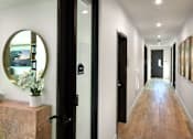 Thumbnail 71 of 94 - A hallway with a round mirror on the wall and a wooden dresser with a vase of flowers on top.