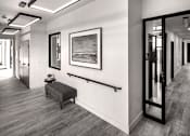 Thumbnail 74 of 94 - A black and white photo of a hallway with a bench and a painting on the wall.