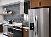 Thumbnail 64 of 94 - A modern kitchen with a stainless steel refrigerator and wooden cabinets.