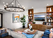 Thumbnail 59 of 94 - A living room with a large sofa, a coffee table, a bookshelf, and a painting on the wall.