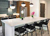 Thumbnail 49 of 94 - A modern kitchen with a white island and black chairs.
