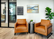 Thumbnail 54 of 94 - Two brown leather chairs are placed in front of a wall with a framed artwork and a plant.