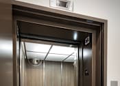 Thumbnail 47 of 94 - A stainless steel elevator with a glass door and a control panel on the right side.