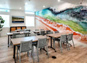 Thumbnail 43 of 94 - A room with a large painting on the wall and several tables and chairs.