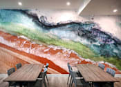 Thumbnail 37 of 94 - A room with a large mural of a beach scene and a table with chairs.