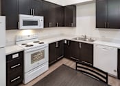 Thumbnail 27 of 94 - A kitchen with black cabinets and white appliances.