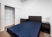 Thumbnail 18 of 94 - A bed with a dark blue cover sits in a room with white walls.